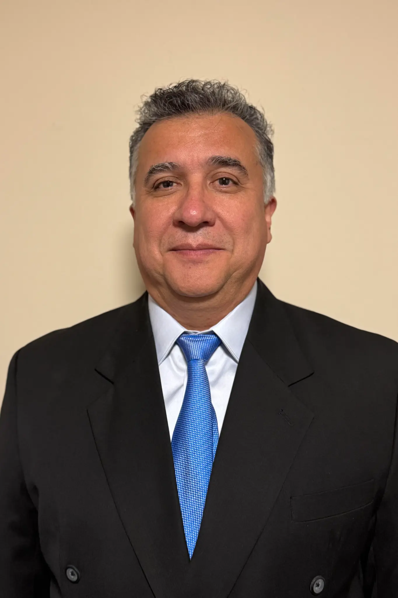 Portrait of Enrique Rivera in a dark suit and blue tie