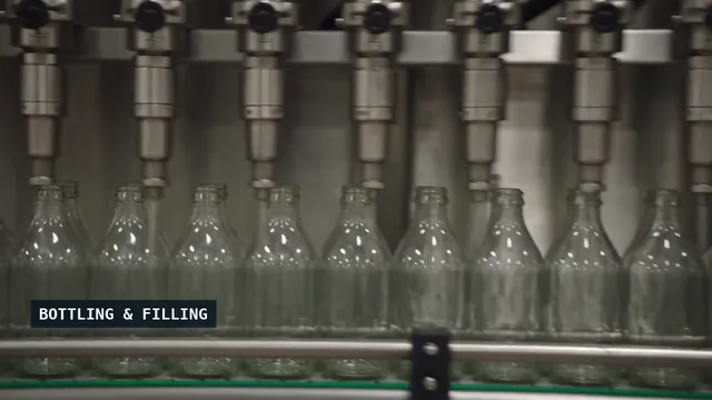 Bottles passing beneath filling nozzles